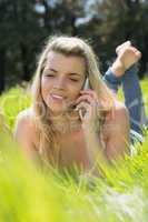 Pretty blonde lying on grass talking on phone