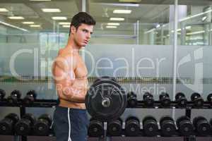 Shirtless muscular man lifting barbell in gym