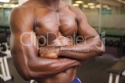 Shirtless muscular man with arms crossed in gym