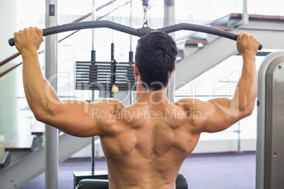 Muscular man exercising on a lat machine in gym