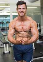 Shirtless muscular man flexing muscles in gym