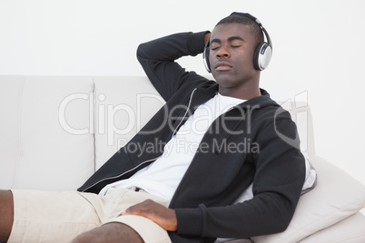 Casual man sitting on sofa enjoying music with eyes closed