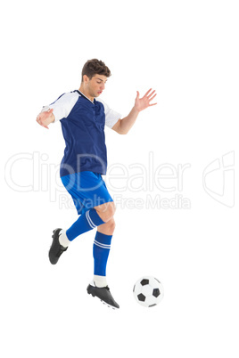 Football player in blue jersey kicking ball