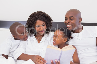 Happy family reading book together in bed