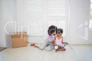 Mother and daughter sitting on the floor reading storybook
