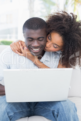 Attractive couple using laptop together on sofa