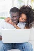 Attractive couple using laptop together on sofa