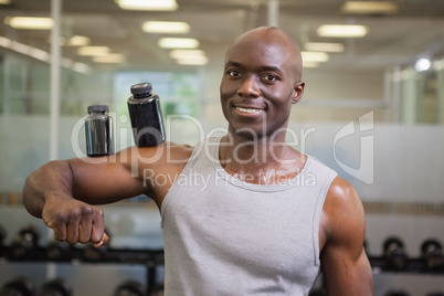 Body builder holding bottles with supplements on biceps