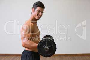 Shirtless muscular man lifting barbell in gym