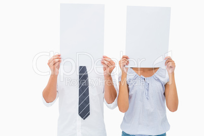 Couple holding paper over their faces