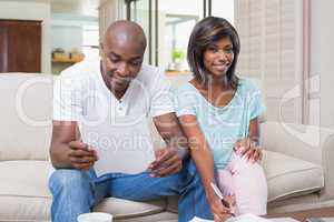 Confident couple calculating bills on the couch