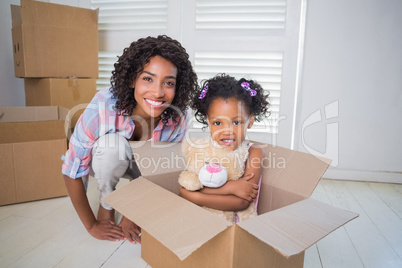 Cute daughter sitting in moving box with mother