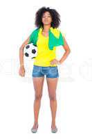 Pretty football fan holding brazilian flag looking at camera