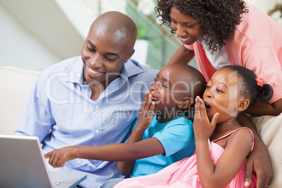 Family relaxing together on the sofa using laptop