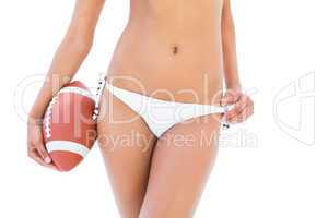 Fit girl in white bikini holding american football