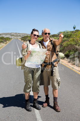 Hiking couple looking at map on the road and pointing ahead