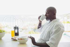 Handsome man in bathrobe having breakfast outside