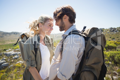 Hiking couple standing on mountain terrain smiling at each other