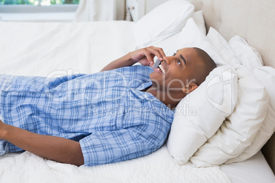 Happy man lying on bed and talking on phone Happy man lying on bed and talking on phone