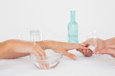 Beautician filing female clients nails at spa beauty salon