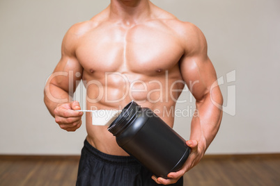 Body builder holding a scoop of protein mix in gym