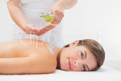 Attractive woman getting massage oil on her back