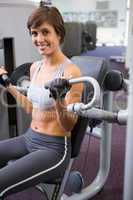 Healthy happy brunette using weights machine for arms