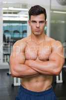 Serious young muscular man in gym