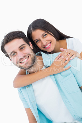 Happy casual man giving pretty girlfriend piggy back