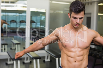 Serious shirtless muscular man in gym