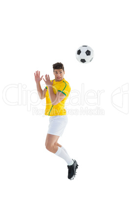 Football player in yellow jersey jumping to ball