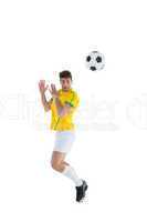 Football player in yellow jersey jumping to ball