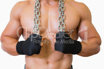 Mid section of a shirtless muscular man holding chain