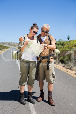 Hiking couple looking at map on the road