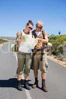 Hiking couple looking at map on the road