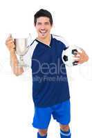 Football player in blue holding winners cup and ball