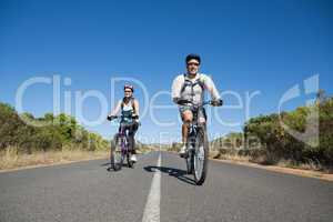 Fit smiling couple going for a bike ride in the countryside