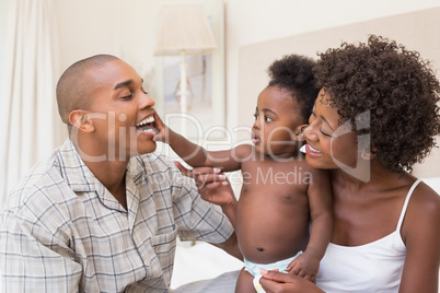 Happy couple on bed with baby daughter