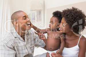 Happy couple on bed with baby daughter