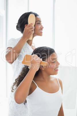 Mother and daughter brushing their hair together