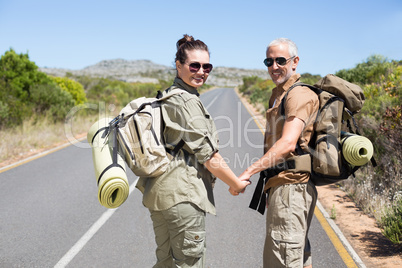 Hitch hiking couple standing holding hands on the road