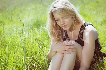 Pretty blonde in sundress sitting on grass