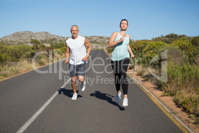 Fit couple running on the open road together