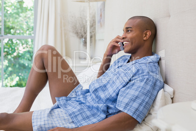 Happy man lying on bed and talking on phone