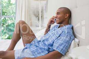 Happy man lying on bed and talking on phone