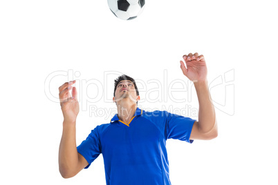 Football player in blue jumping to ball