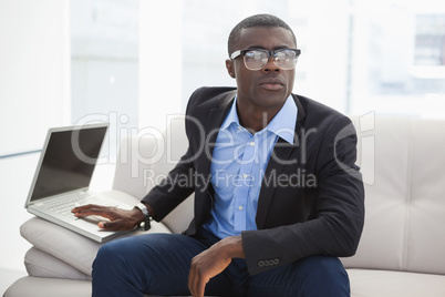 Hipster businessman sitting on couch with laptop