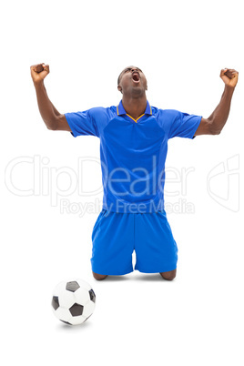 Excited football player in blue cheering on his knees