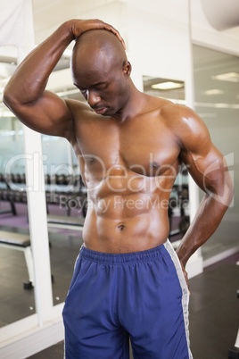 Serious shirtless muscular man posing in gym