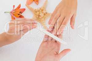 Beautician filing female clients nails at spa beauty salon